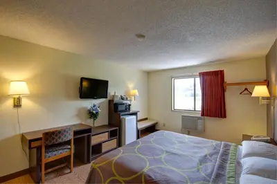 a hotel room with a bed and a desk and a television at Super 8 by Wyndham Zanesville in Zanesville