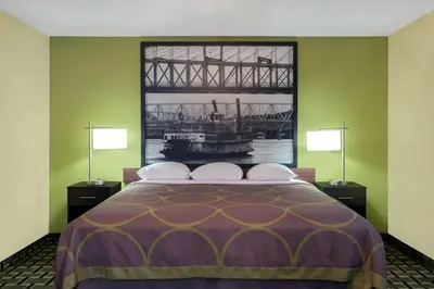 a bedroom with a bed with a large picture of a bridge at Super 8 by Wyndham Marietta in Marietta