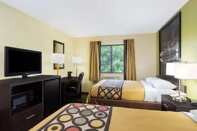 a hotel room with two beds and a flat screen tv at Super 8 by Wyndham Marietta in Marietta