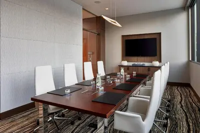 a conference room with a long wooden table and white chairs at AC Hotel by Marriott Cleveland Beachwood in Beachwood