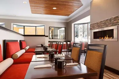 a restaurant with tables and chairs and a fireplace at Radisson Akron-Fairlawn Copley in Fairlawn