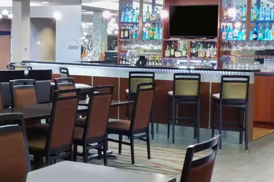 a restaurant with tables and chairs and a bar at Radisson Akron-Fairlawn Copley in Fairlawn