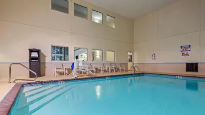 a swimming pool in a building with chairs around it at Best Western Gas City in Gas City
