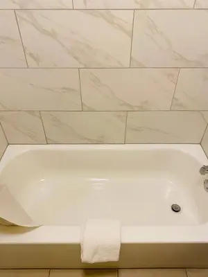 a white bath tub in a bathroom with a tile wall at Highlander Motel in Athens