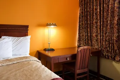 a hotel room with a bed and a desk with a lamp at Highlander Motel in Athens