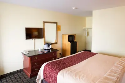 a hotel room with a bed and a dresser and a mirror at Highlander Motel in Athens