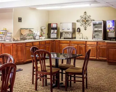 a dining room with a table and chairs and a kitchen at Quality Inn Lima Northeast in Lima