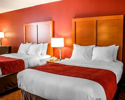 two beds in a hotel room with red walls at Quality Inn Lima Northeast in Lima