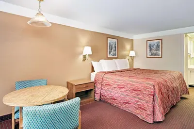 a hotel room with a bed and a table and chairs at Knights Inn Charleston West Virginia in Charleston