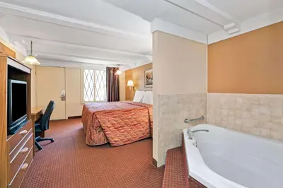 a hotel room with a bath tub and a bed at Knights Inn Charleston West Virginia in Charleston