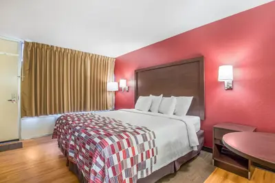 a hotel room with a large bed and a table at Red Roof Inn Cincinnati Airport–Florence/ Erlanger in Erlanger