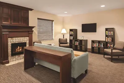 a living room with a fireplace and a desk and chair at Country Inn & Suites by Radisson, Dayton South, OH in Dayton