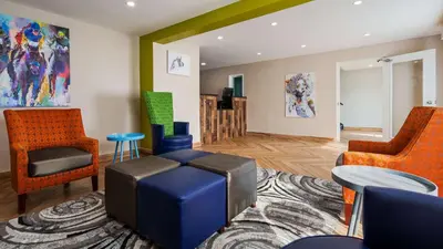 a living room with orange and blue chairs at SureStay Hotel by Best Western Florence in Florence