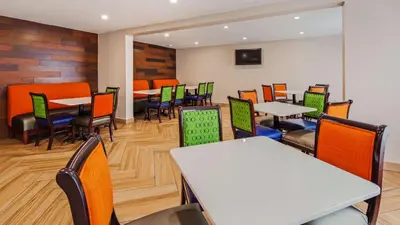 a dining room with tables and chairs and a tv at SureStay Hotel by Best Western Florence in Florence