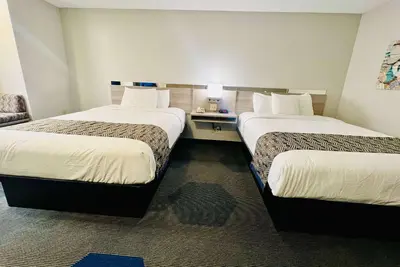 a hotel room with two beds and a chair at Microtel Inn Georgetown - Lexington North in Georgetown