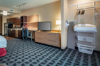 a room with a desk with a tv and a kitchen at TownePlace Suites by Marriott Toledo Oregon in Oregon