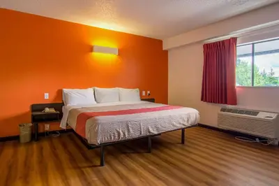 a bedroom with a bed with an orange wall at Motel 6-Ashland, OH in Ashland