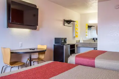 a room with two beds and a table and a kitchen at Motel 6-Ashland, OH in Ashland