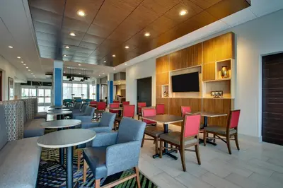 a waiting room with tables and chairs and a flat screen tv at Holiday Inn Express & Suites Findlay North by IHG in Findlay