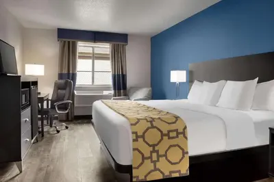 a hotel room with a large bed and a desk at Baymont Toledo Airport Hotel Swanton in Swanton