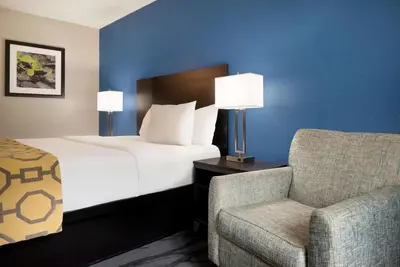 a hotel room with a bed and a chair at Baymont Toledo Airport Hotel Swanton in Swanton
