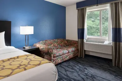 a hotel room with a bed and a chair and a window at Baymont Toledo Airport Hotel Swanton in Swanton