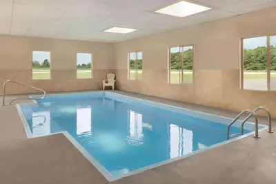a large swimming pool in a room with windows at Baymont Toledo Airport Hotel Swanton in Swanton