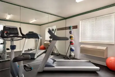 a gym with a treadmill and exercise equipment in a room at Baymont Toledo Airport Hotel Swanton in Swanton