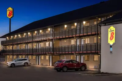 two cars parked in a parking lot in front of a building at Super 8 by Wyndham Vandalia/Dayton International Airport in Vandalia