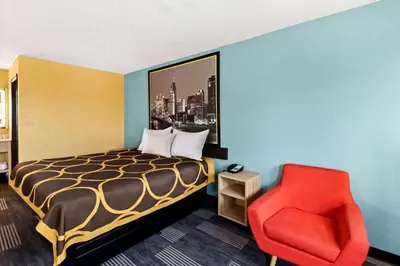 a hotel room with a bed and a red chair at Super 8 by Wyndham Vandalia/Dayton International Airport in Vandalia