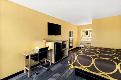 a hotel room with a bed and a desk with a computer at Super 8 by Wyndham Vandalia/Dayton International Airport in Vandalia
