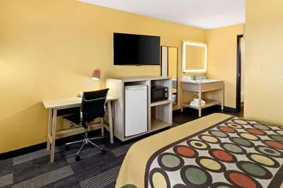 a hotel room with a bed and a desk and a tv at Super 8 by Wyndham Vandalia/Dayton International Airport in Vandalia