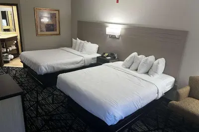 a hotel room with two beds and a chair at Baymont By Wyndham Monroe Ohio in Monroe