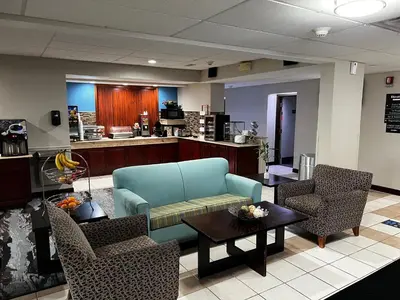 a waiting room with a couch and chairs and a table at Baymont By Wyndham Monroe Ohio in Monroe