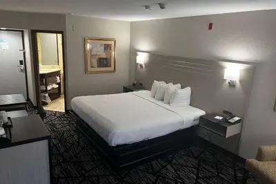 a hotel room with a large bed with white sheets at Baymont By Wyndham Monroe Ohio in Monroe