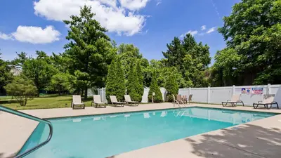 a swimming pool with chaise lounge chairs and trees at Best Western PLUS Hannaford Inn & Suites in Cincinnati