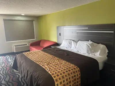a bedroom with a large bed and a red chair at Blue Stone Inn in Washington Court House