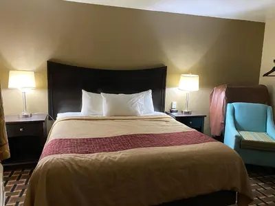 a hotel room with a bed and a blue chair at Executive Inn Chillicothe in Chillicothe
