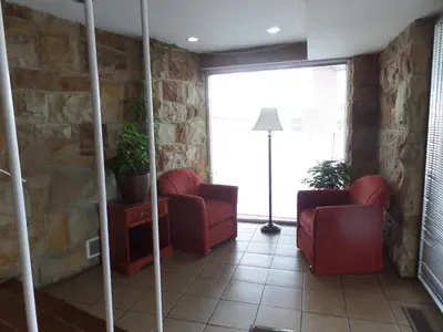 a living room with two red chairs and a stone wall at Executive Inn Chillicothe in Chillicothe