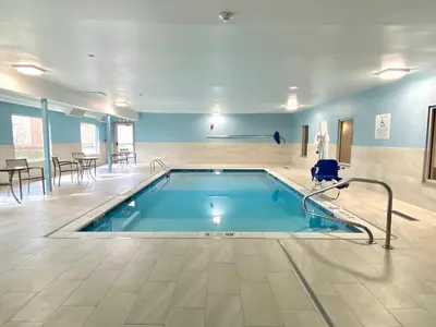 a swimming pool in a large room with tables and chairs at Holiday Inn Express & Suites Elyria by IHG in Elyria