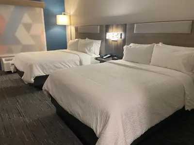 two beds in a hotel room with white sheets at Holiday Inn Express & Suites Elyria by IHG in Elyria