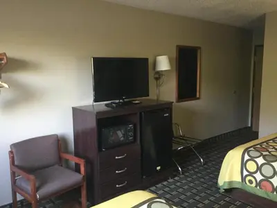 a hotel room with a tv and a chair and a bed at Super 8 by Wyndham Youngstown/Austintown in Youngstown