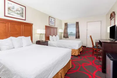 a hotel room with two beds and a flat screen tv at Travelodge by Wyndham Richmond IN in Richmond