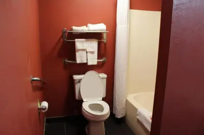 a bathroom with a toilet and towels on a red wall at Travelodge by Wyndham Richmond IN in Richmond