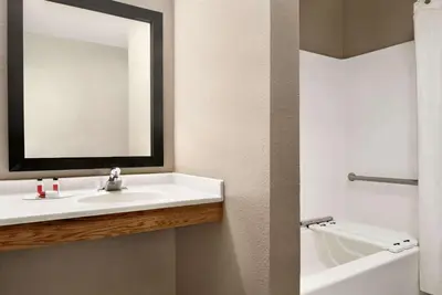 a bathroom with a sink and a mirror and a tub at Super 8 by Wyndham Akron S/Green/Uniontown OH in Uniontown