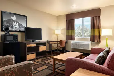 a hotel room with a television and a living room at Super 8 by Wyndham Akron S/Green/Uniontown OH in Uniontown