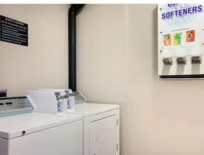 a white laundry room with a washer and a poster at Super 8 by Wyndham Akron S/Green/Uniontown OH in Uniontown