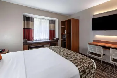 a hotel room with a bed and a flat screen tv at Microtel Inn & Suites by Wyndham Sunbury - Columbus North in Sunbury
