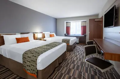 a hotel room with two beds and a flat screen tv at Microtel Inn & Suites by Wyndham Sunbury - Columbus North in Sunbury