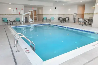 a large swimming pool in a hotel room with tables and chairs at Hilton Garden Inn Cincinnati Midtown in Cincinnati